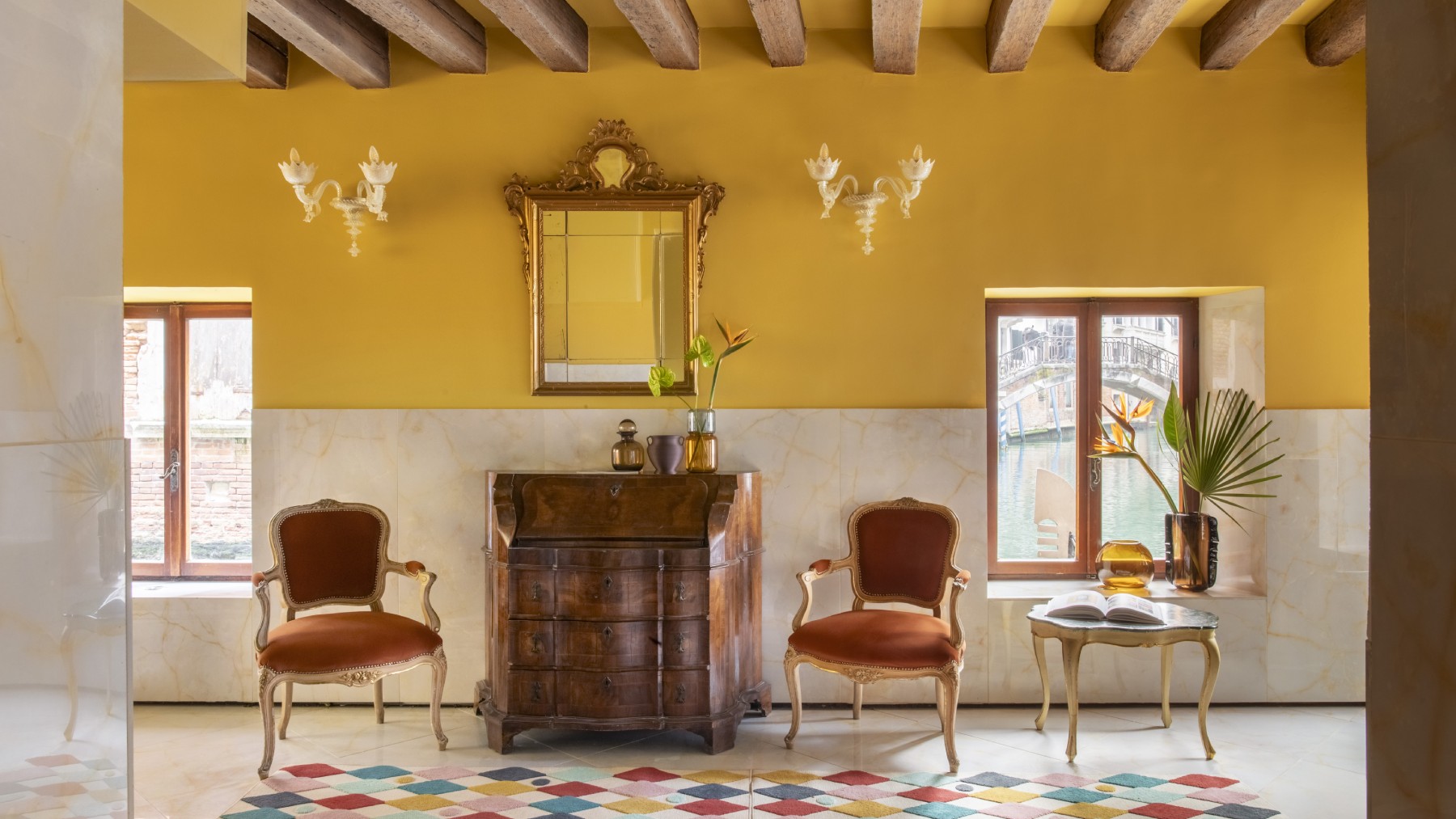 Design lounge area Hotel Riva featuring mustard yellow walls, vintage furniture, exposed beams, and canal-view windows - Hotel Riva, BZAR hotels in Venice