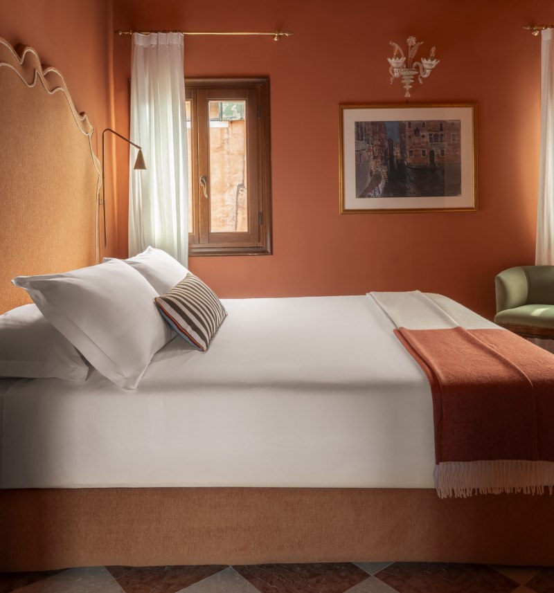 Warm terracotta bedroom interior with checkered marble floors and Venetian art - Hotel Riva, BZAR hotels in Venice